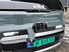 Front på Kia PV5 Cargo med åpen ladeport og norsk elbilskilt på snødekt underlag.
