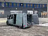 Grønn Kia PV5 varebil med åpne dører parkert ved lasteramper på terminal.