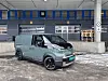 Elektrisk Kia PV5 Cargo varebil parkert foran lasteramper på et industriområde.