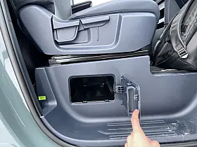 Nærbilde av gjennomlastingsluke i plastpanel ved forsetet i en Kia varebil.
