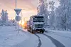 Elektrisk Mercedes eArocs 400 lastebil kjører på snødekt vei i vinterlandskap ved solnedgang.